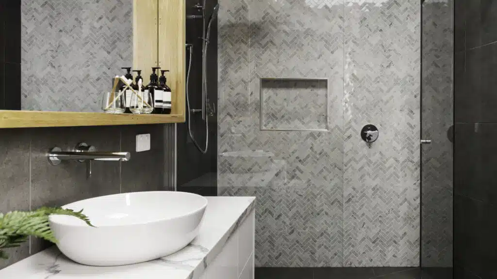 Newly remodeled residential bathroom with a herringbone tile shower. 