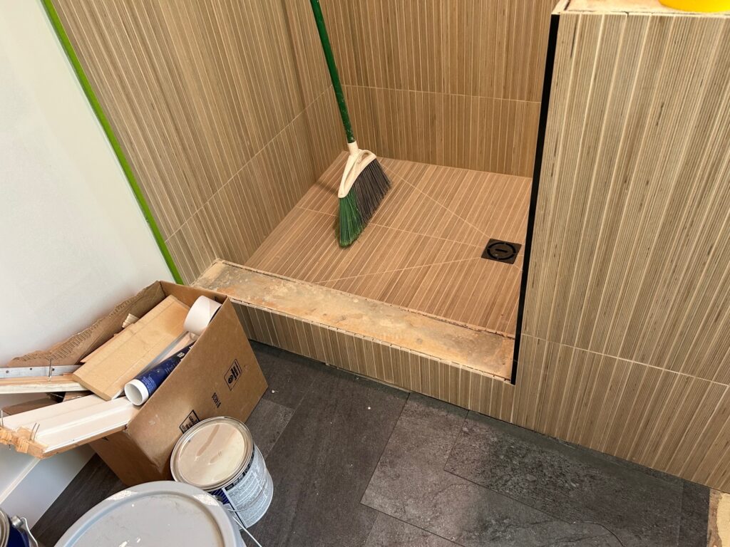 The shower tile is almost all installed. Our team is sweeping up to move to the next step.