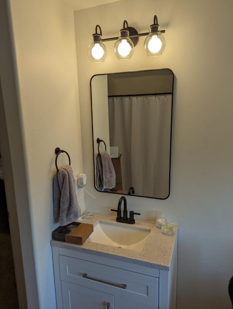 Single bathroom vanity with new mirror and lighting. 